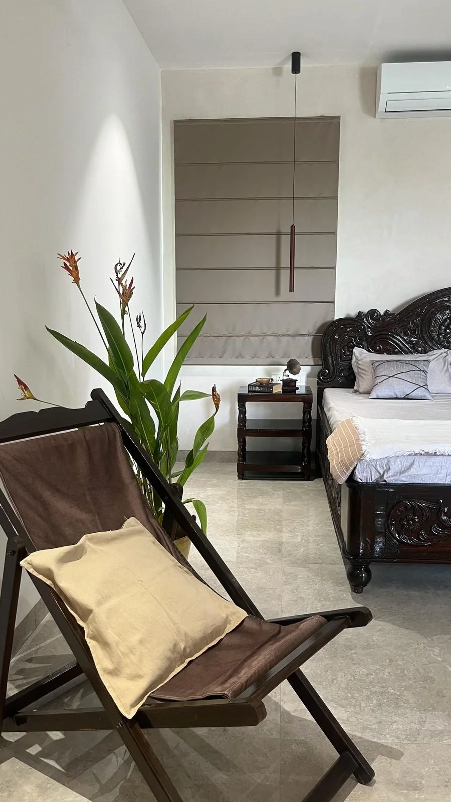 An'teak Villa, Hyderabad — bedroom with an antique carved bed and a Roman blind