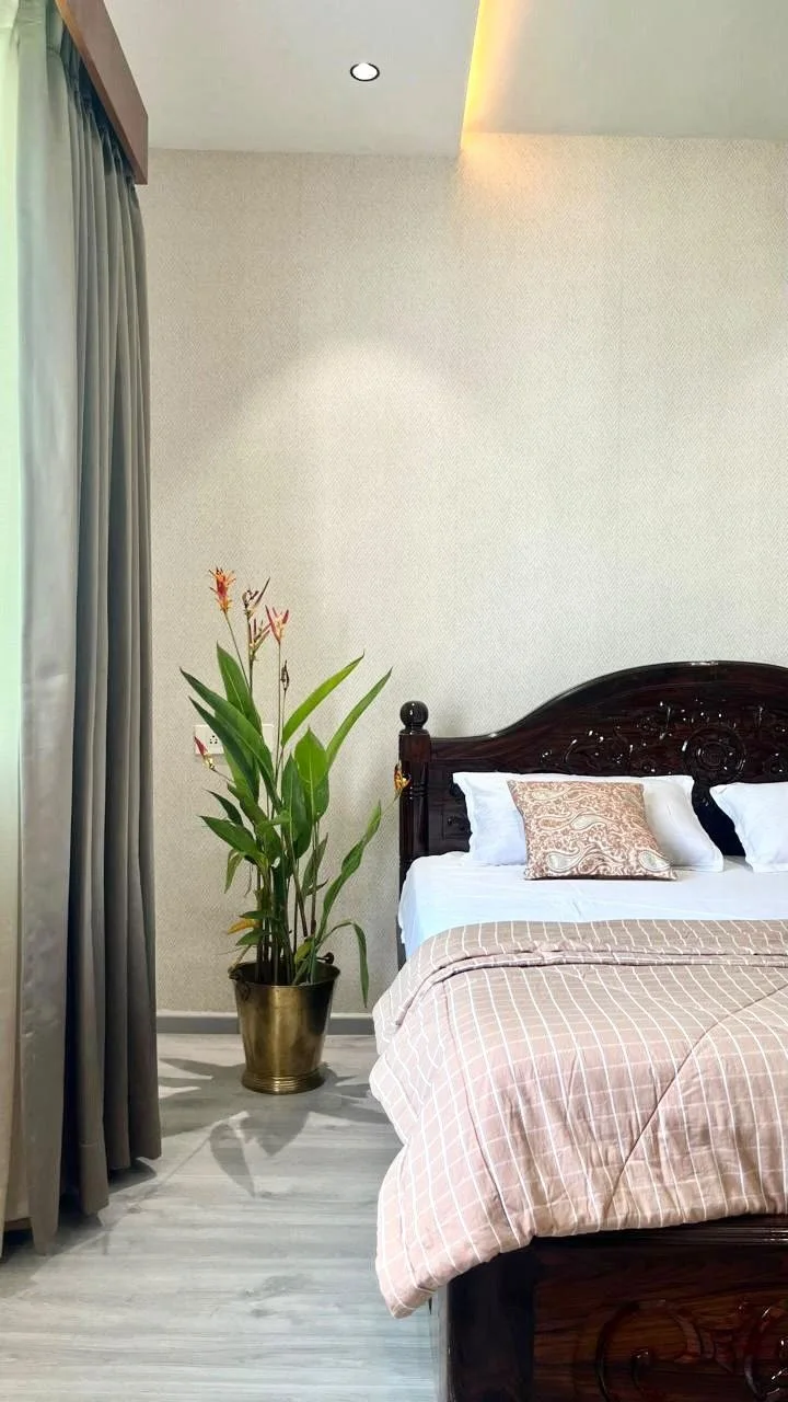 An'teak Villa, Hyderabad — bedroom with an antique carved bed, full-height curtains and a textured wall