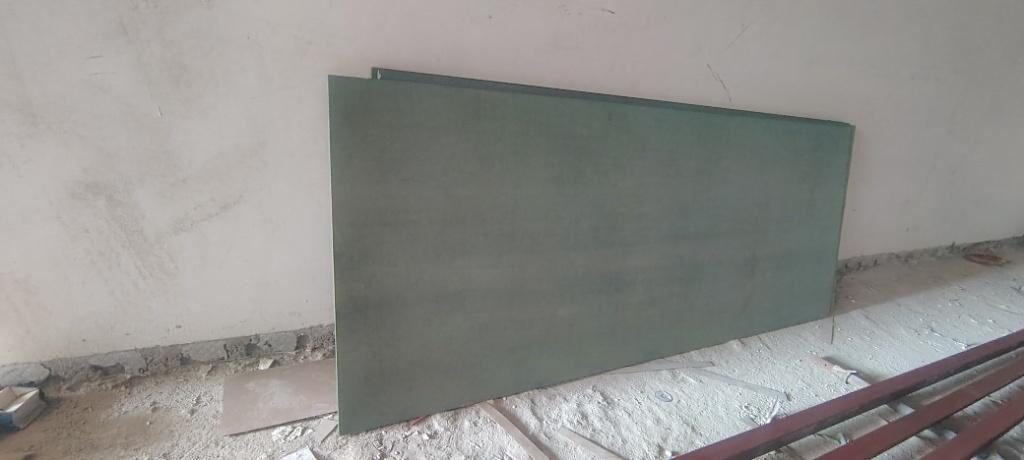 Board panel stacked against the wall at the kiosk location before frame erection