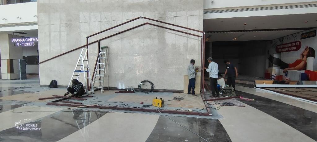 Workers bracing the kiosk frame with ladders in position